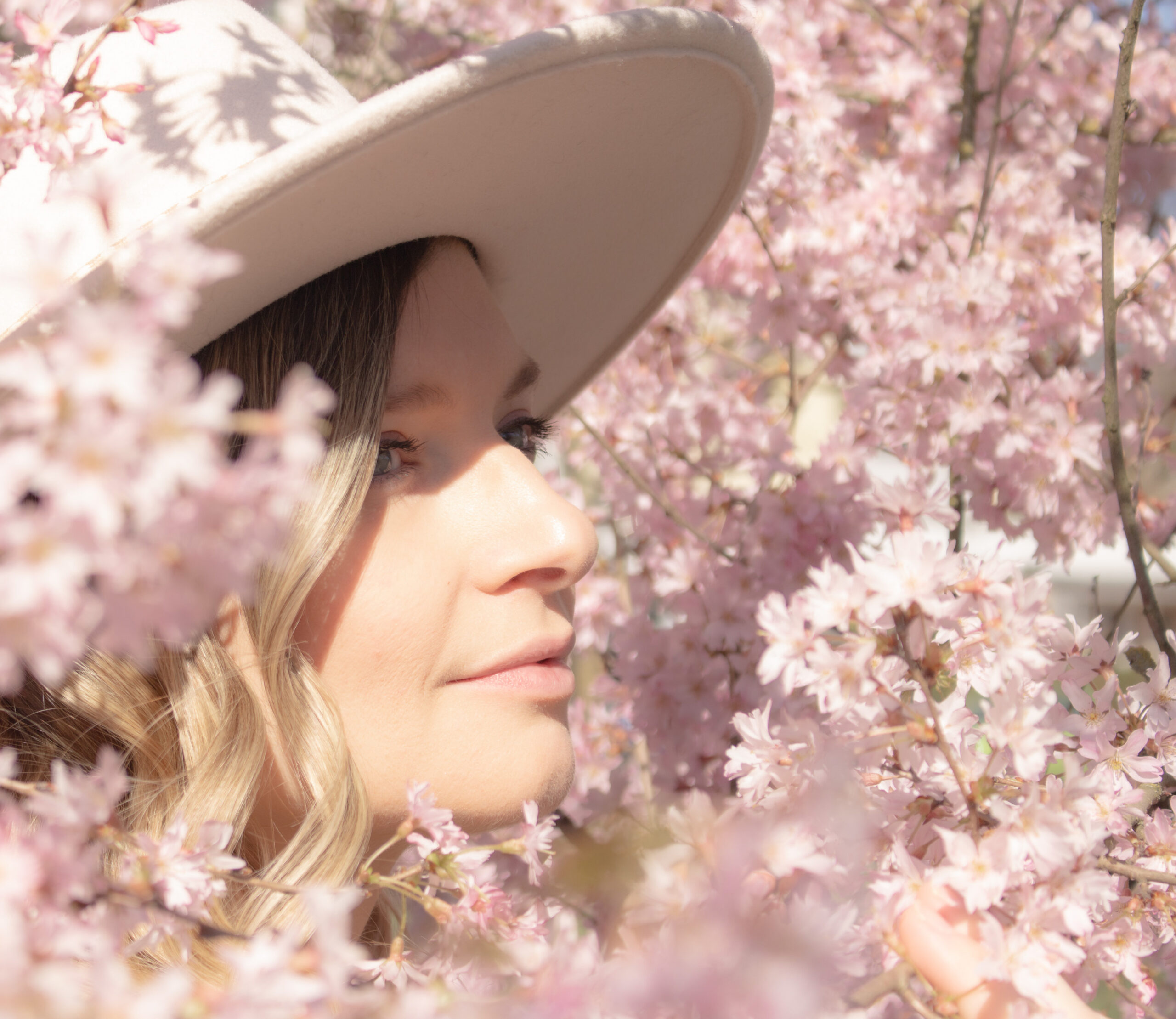 Seitliches Portrait einer Frau mit Hut in Kirschbl&uuml;ten