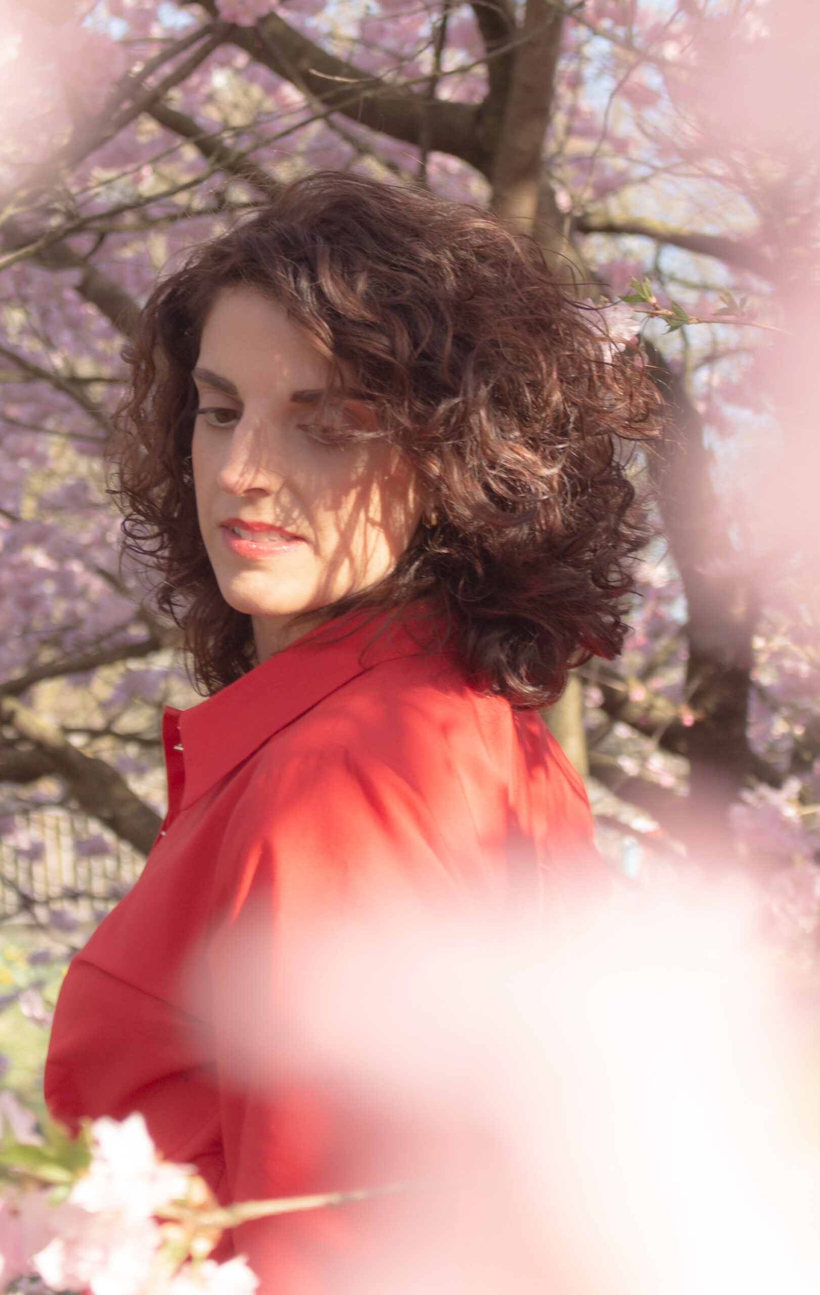 Portrait einer Frau in rotem Kleid unter Kirschbl&uuml;ten